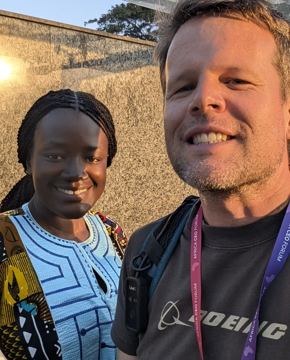 Journalist wearing a LiveU live-transmission pack, reporting alongside a colleague at the Africa CEO Forum