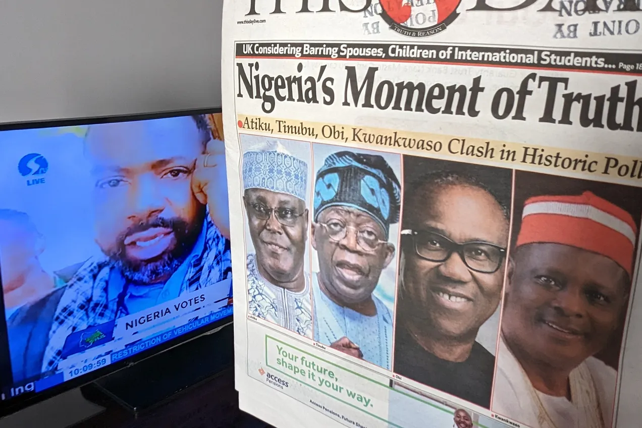 A Nigerian newspaper front page headlined “Nigeria's Moment of Truth” propped beside a television carrying live election coverage