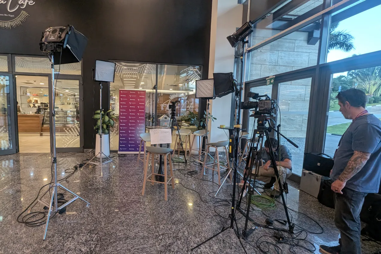 Broadcast lights, a camera on sticks and crew setting up an interview position in a hotel lobby in Kigali